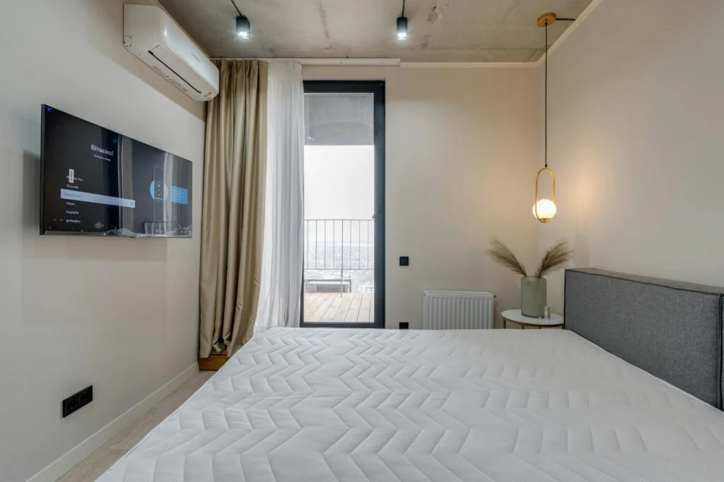 Tv instalado en la pared, y un aire acondicionado en una habitacion iluminada